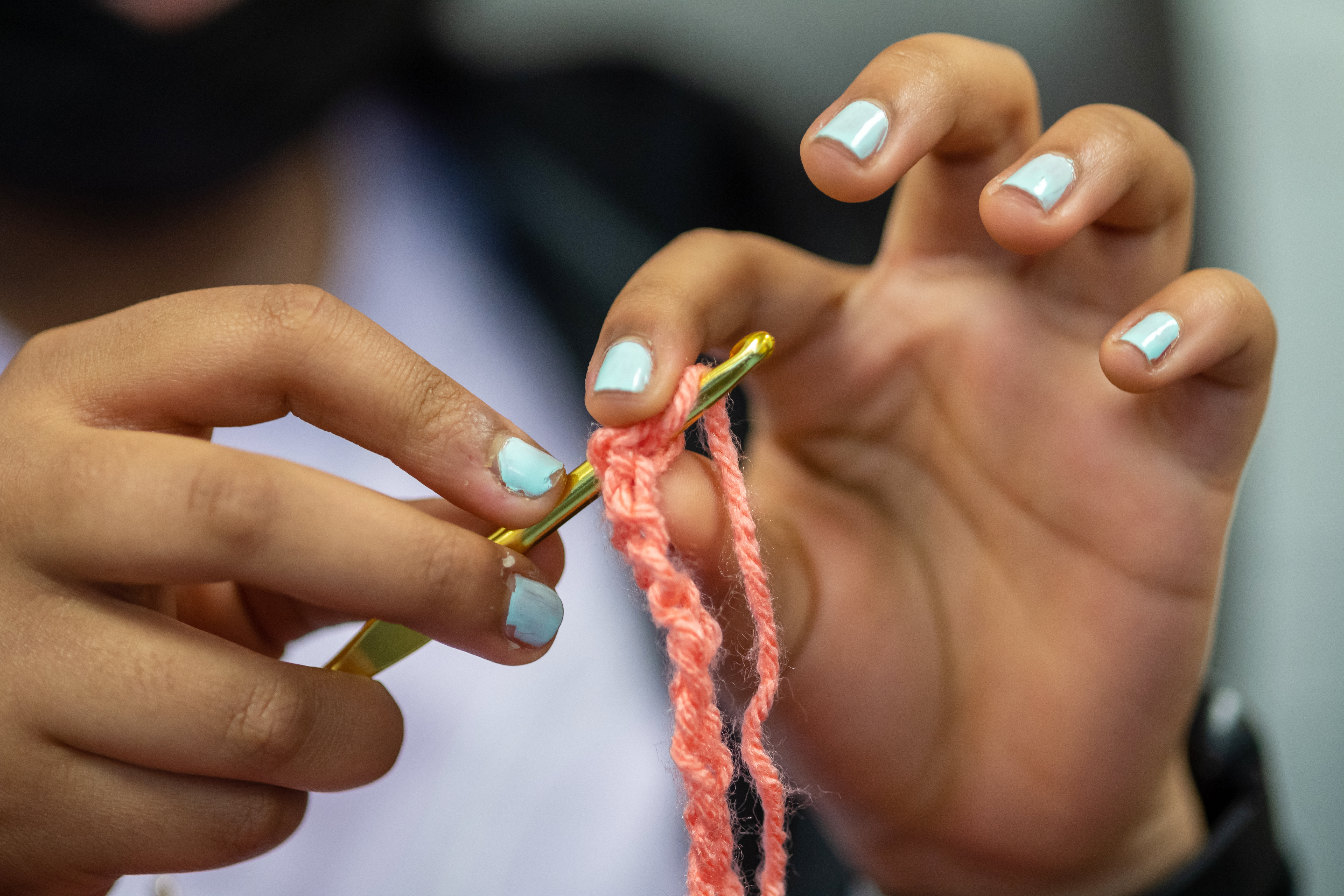 A student at Katherine Johnson Middle School crochets with pink yarn.