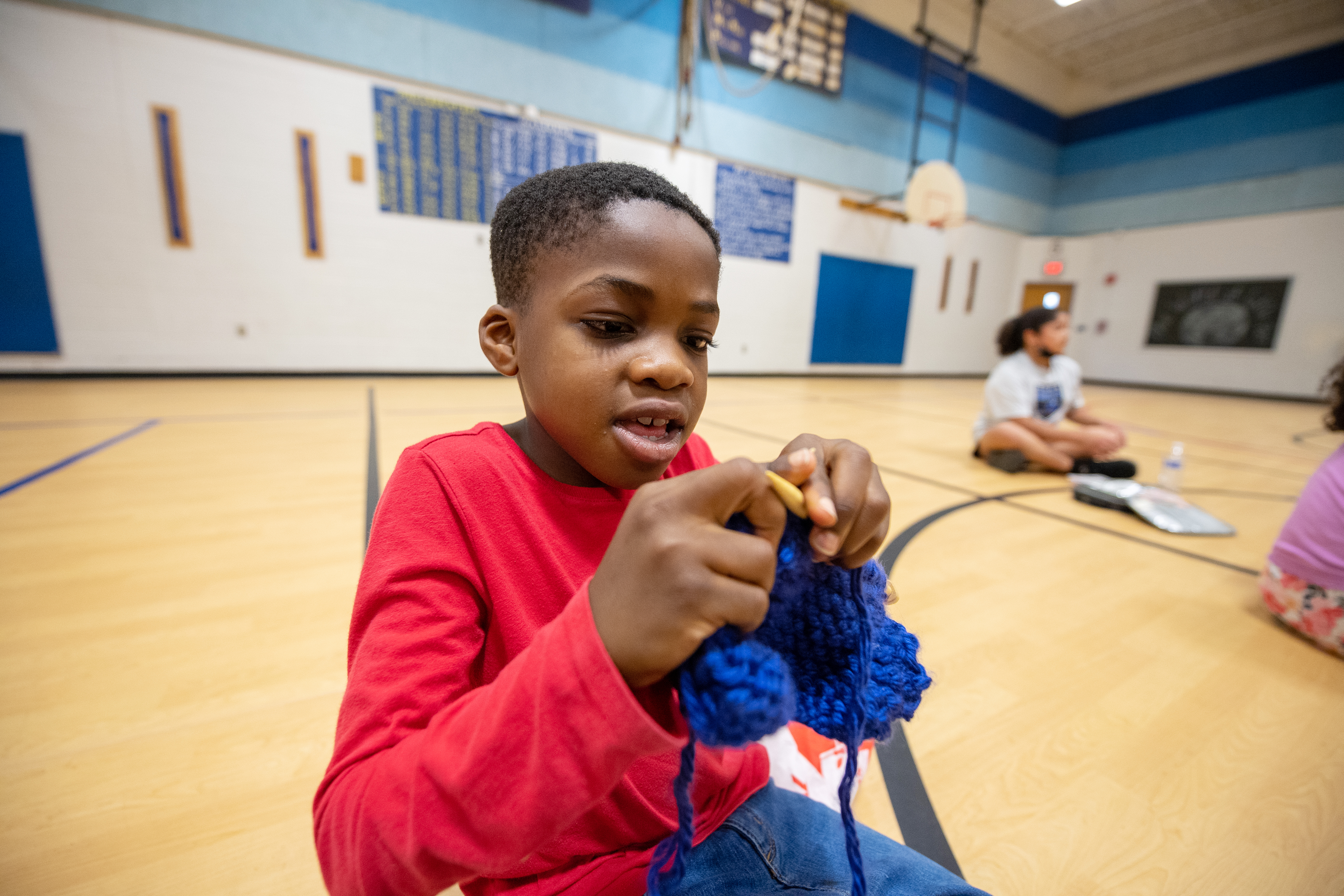 A third-grader at Little Run Elementary continues work on a scarf he has learned to knit through his school's program.