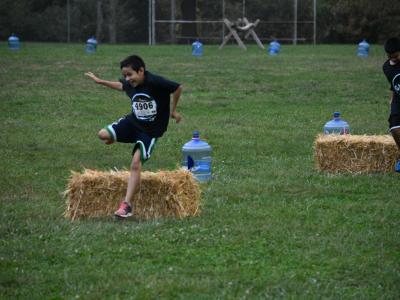 photo of boy jumping over a bail of hay