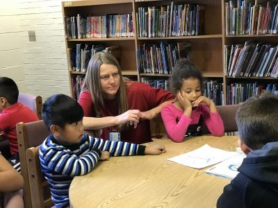photo of librarian and students reading together in the library